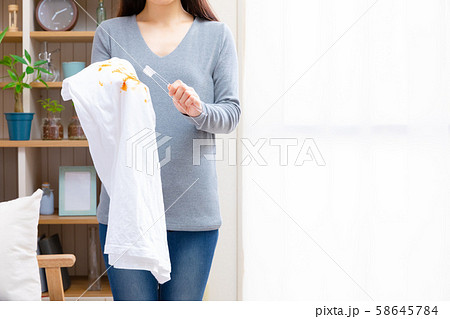 歯ブラシで服の汚れを落とす女性 歯ブラシで服の汚れを落とす女性 58645784