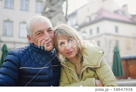 Handsome elderly man is embracing his young blonde wife spending time together outdoors in the Handsome elderly man is embracing his young blonde wife spending time together outdoors in the 58647938
