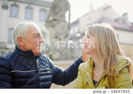 Handsome elderly man is embracing his young blonde wife spending time together outdoors in the 58647950