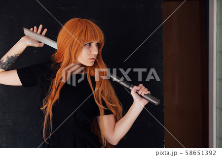 Woman cosplayer anime with red hair holds a Japanese sword 58651392