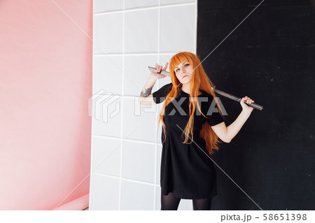 Woman cosplayer with red hair holds Japanese sword 58651398
