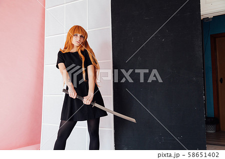 Woman cosplayer with red hair holds Japanese sword 58651402