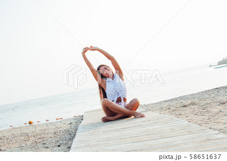 Beautiful woman with long hair doing yoga on the beach by the sea 58651637
