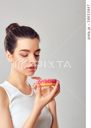 Close up portrait of a hungry girl eating donuts 58653847