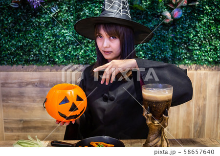 Beautiful young surprised woman or Halloween Witch dark style with holding a pumpkin and black drink in Halloween celebrate night party. Copy space background and soft or select focus Beautiful young surprised woman or Halloween Witch dark style with holding a pumpkin and black drink in Halloween celebrate night party. Copy space background and soft or select focus 58657640