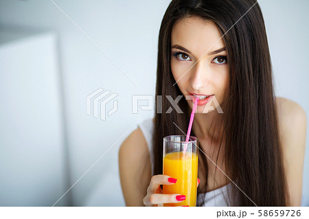 Casual smiling woman holding a glass of orange juice Casual smiling woman holding a glass of orange juice 58659726