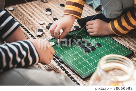 Closeup of kids hands playing reversi or othello traditional strategic board game by thinking, planing and use fingers flip the black reversible disc. Cognitive skills, Mind sport, Competitive concept 58660995