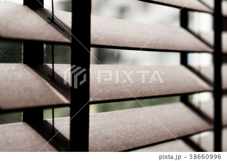 Closeup of a wooden window venetian blinds in the bedroom full of tiny pieces of particle dust which come from the power plants, factories, construction sites. It can cause allergies. Air pollution. Closeup of a wooden window venetian blinds in the bedroom full of tiny pieces of particle dust which come from the power plants, factories, construction sites. It can cause allergies. Air pollution. 58660996