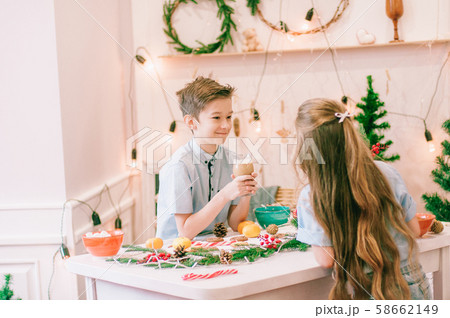 Cute little sister with long hair and an older brother drink cocoa in anticipation of Christmas. Christmas mood 58662149