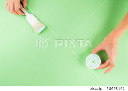 Hand with paint brush on green mint background 58663161