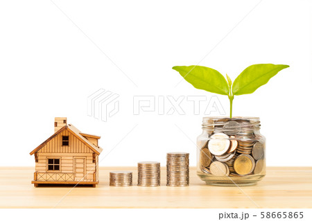 Coin jar and stack, and model house on wooden desk 58665865