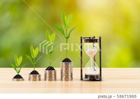 Coin stack with growing leaves and hourglass on 58671900