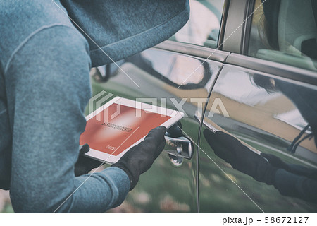 Hooded thief tries to break the car's security Hooded thief tries to break the car's security 58672127