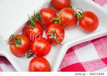 brie cheese and cherry tomatoes on red tablecloth. brie cheese and cherry tomatoes on red tablecloth. 58672899