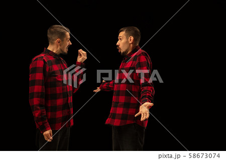Young handsome man arguing with himself on black studio background. Young handsome man arguing with himself on black studio background. 58673074