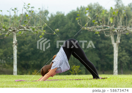 Young beautiful woman doing yoga exercise in green park. Healthy lifestyle and fitness concept. 58673474