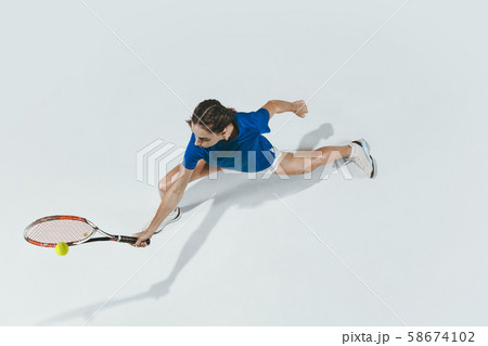 Young woman in blue shirt playing tennis. Youth, flexibility, power and energy. 58674102