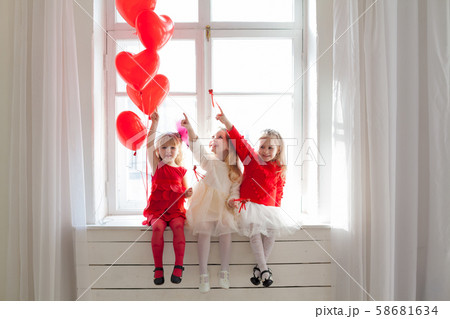 Three girl girlfriends sit by the window with balloons Three girl girlfriends sit by the window with balloons 58681634