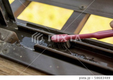 ピンクの歯ブラシでサッシレールを掃除する 58683489
