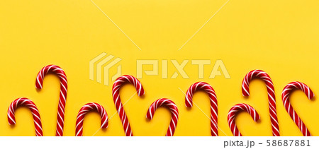 Banner with Christmas lollipops on yellow background. Colorful holiday sweets with bright copy space. Traditional dessert wtih red and white stripes. Banner with Christmas lollipops on yellow background. Colorful holiday sweets with bright copy space. Traditional dessert wtih red and white stripes. 58687881