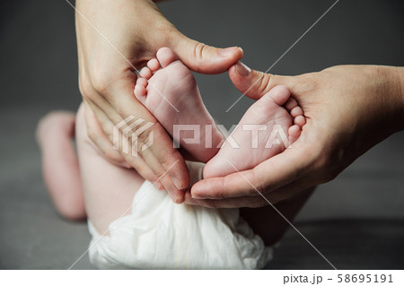 Mother holding newborn baby feet in hands 58695191