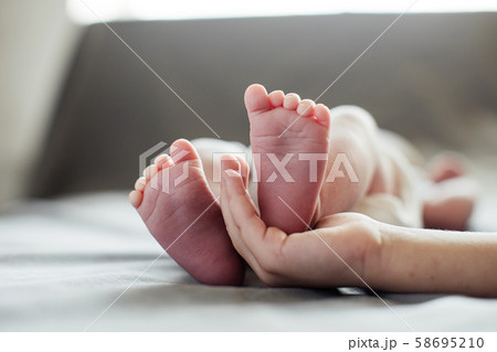 Mother holding newborn baby feet in hands 58695210
