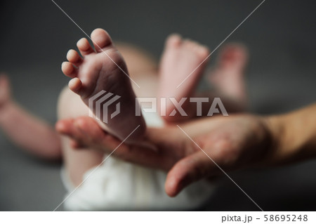 Mother holding newborn baby feet in hands Mother holding newborn baby feet in hands 58695248