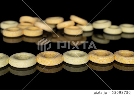 Pale round candy isolated on black glass 58698786
