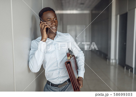 Businessman talking by phone in office hallway Businessman talking by phone in office hallway 58699303