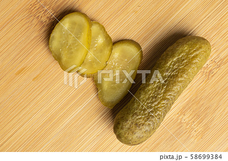 Sour green pickles on light wood 58699384