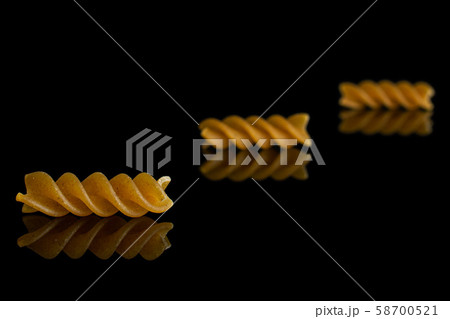 Dry wholegrain fusilli isolated on black glass Dry wholegrain fusilli isolated on black glass 58700521