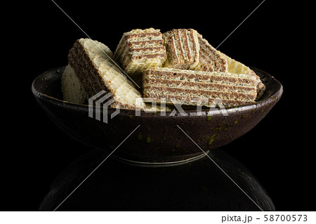 Hazelnut wafer cookie isolated on black glass 58700573