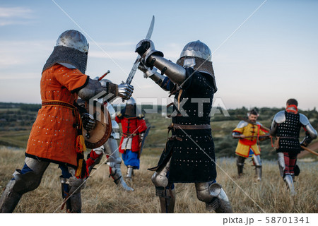 Knights in armour and helmets fight with swords 58701341