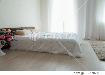 White bedroom bright interiors with bed and flowers White bedroom bright interiors with bed and flowers 58702865