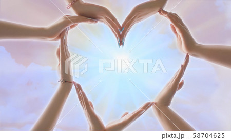A group of youth makes a heart shape out of their hands. 58704625