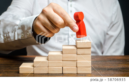 A man puts a red human figure on top of the stairs. Career growth, improvement of skills. Promotion at work of employees to leading post. The concept of success. Training. Education, business 58706935