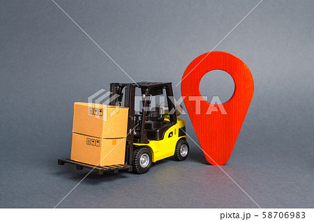 Yellow forklift carries boxes and a red location pointer. Transportation services and logistics management in production warehouse. Destination cargo, tracking. Technological processes at factory 58706983