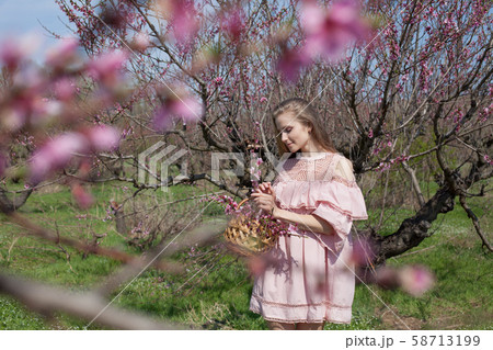 Beautiful blonde woman in dress collects flowers in the garden 58713199