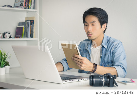 Asian Photographer or Freelancer Checking Work Schedule in Notebook in Vintage Tone 58713348