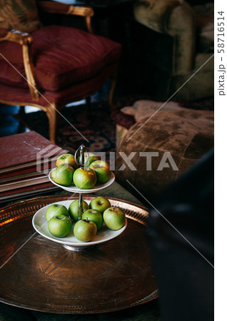 Green apple in ceramic fruit tray on antique brass table 58716514