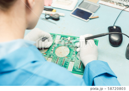 Technician soldering components to a PCB 58720803