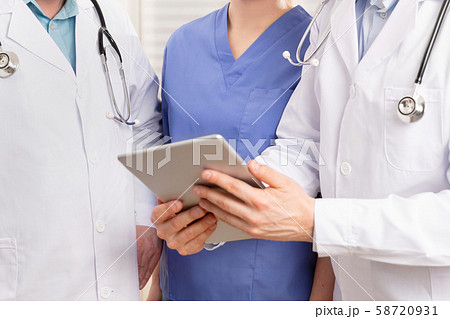 Doctor and medical team discussing patient report at tablet computer in hospital 58720931