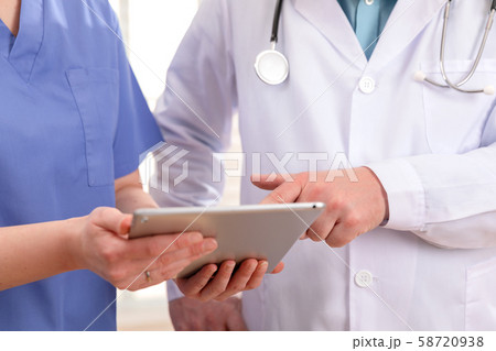 Doctor and nurse discussing patients tests at tablet computer in hospital 58720938