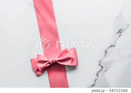 Coral silk ribbon and bow on marble background, 58722366
