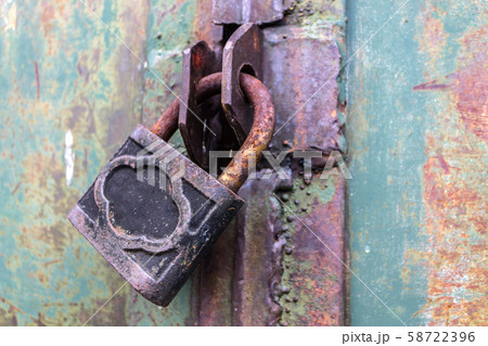 Old and rusty padlock with scratches locks the steel doors of an abandoned vault 58722396