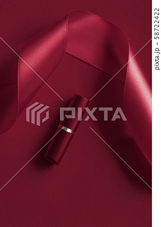 Luxury lipstick and silk ribbon on maroon holiday Luxury lipstick and silk ribbon on maroon holiday 58722422