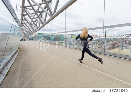 Female runner during fast running exercise in modern city at cloudy day. 58722840