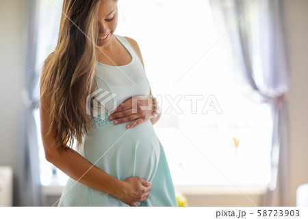 Smiling pregnant woman in dress with her hands at belly Smiling pregnant woman in dress with her hands at belly 58723903
