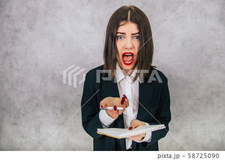 Cute business women standing holding notebook and pen, looking at the camera with shocked, asking Cute business women standing holding notebook and pen, looking at the camera with shocked, asking 58725090