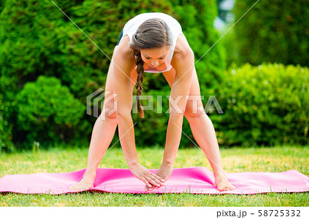Pregnant Woman Doing Forward Bend With Legs Apart In Park 58725332